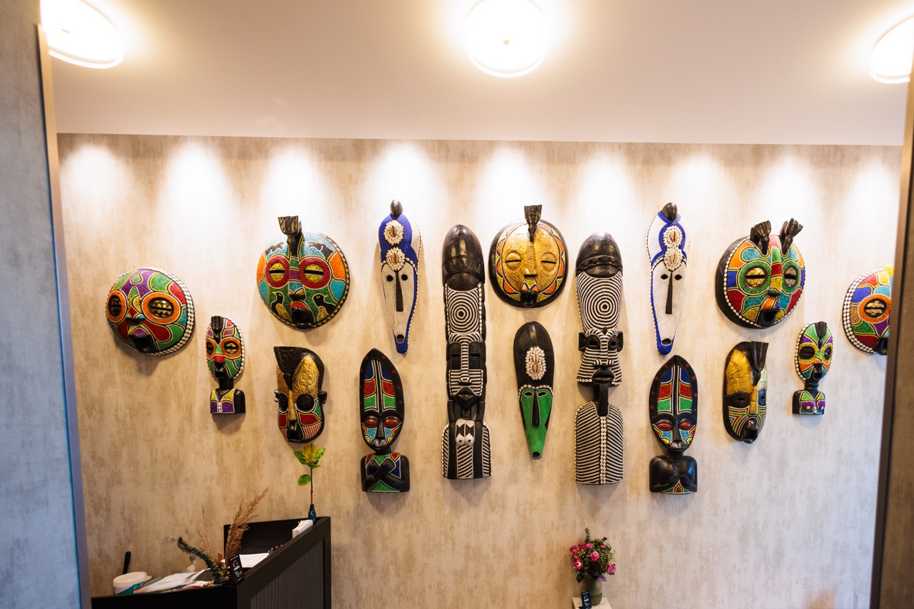 A striking display of handcrafted African masks adorning the wall at OU LA restaurant. These vibrant and intricately designed masks add a cultural and artistic touch to the modern dining space, enhancing the restaurant’s Caribbean-inspired ambiance.